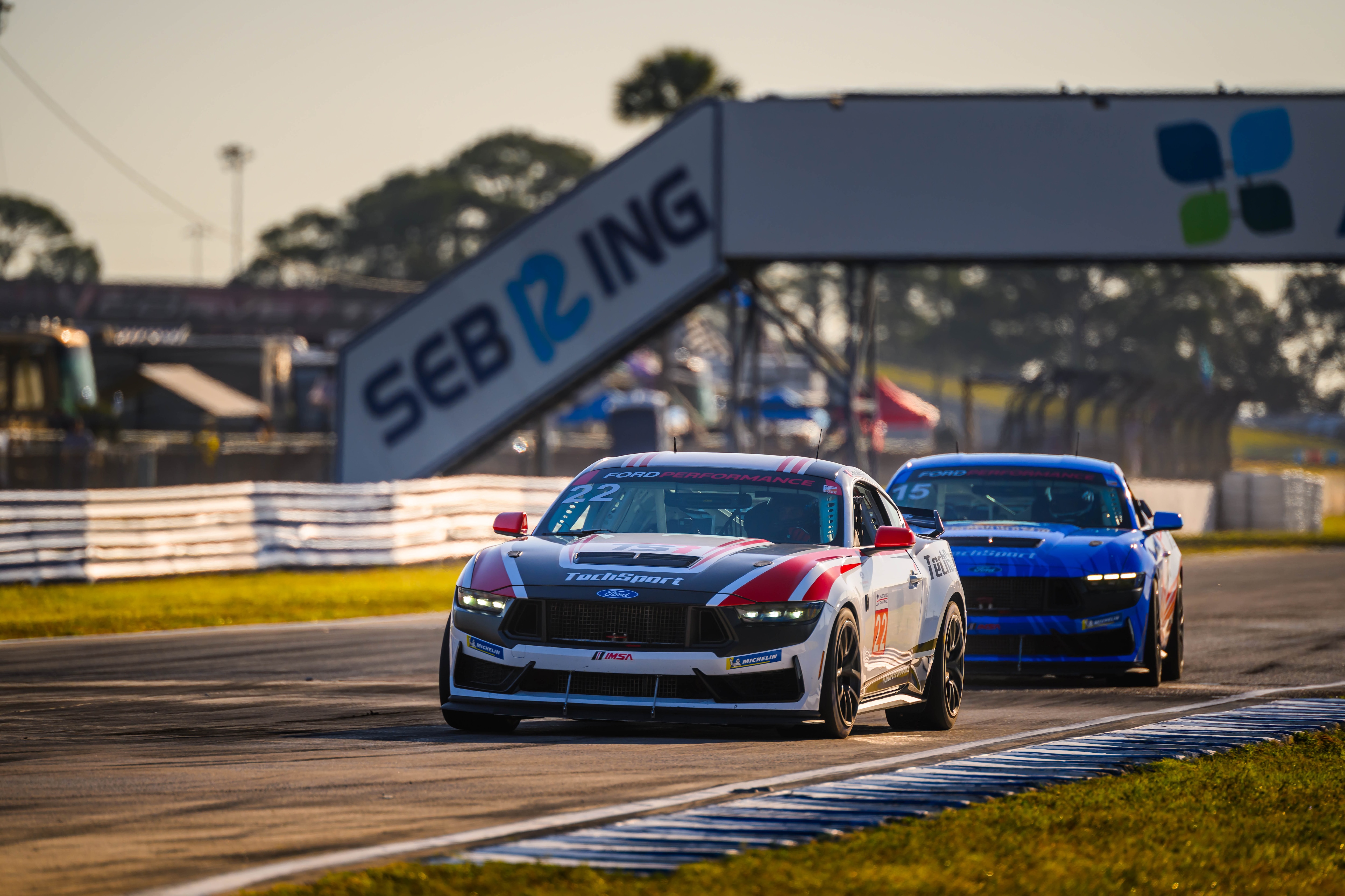 One Mustang behind another on a racetrack.